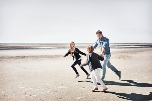 Father with two children running on the beach
